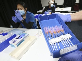 Helen Briggs, a pharmacist, holds up a tray of syringes as Lirie Palamind an RPN (background) loads up them up with Pfizer-BioNTech COVID-19 vaccine at the Humber River Hospital clinic held at Downsview Arena on April 21, 2021.