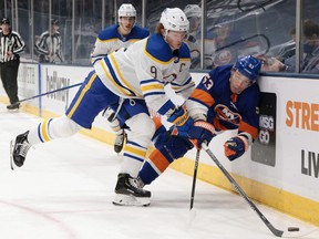 Jack Eichel #9 of the Buffalo Sabres checks Casey Cizikas #53 of the New York Islanders into the boards during the second period at the Nassau Coliseum on March 07, 2021 in Uniondale, New York.