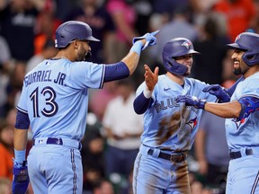 Marcus Semien #10 of the Toronto Blue Jays celebrates with Lourdes Gurriel Jr. #13 and Cavan Biggio #8 after hitting a three-run home run during the ninth inning against the Houston Astros at Minute Maid Park on May 8, 2021 in Houston, Texas.