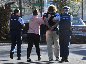 A man is detained by police officers after a stabbing incident at the Countdown supermarket, in Dunedin, New Zealand, May 10, 2021.