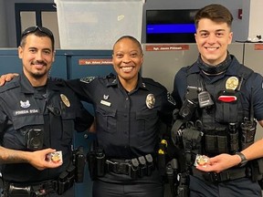 Austin Police officers Eddie Pineda, left, and Chandler Carrera, right, receive the chief's coin of recognition from Chief Robin Henderson  for rescuing a man from a burning pickup.