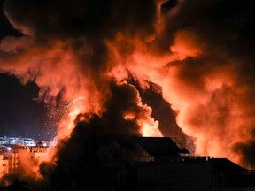 Explosions light-up the night sky above buildings in Gaza City as Israeli forces shell the Palestinian enclave, early on May 18, 2021.