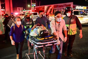 Emergency workers move an injured person on a stretcher at the site of a train accident after an elevated metro line collapsed in Mexico City on May 3, 2021. (Photo by PEDRO PARDO/AFP via Getty Images)