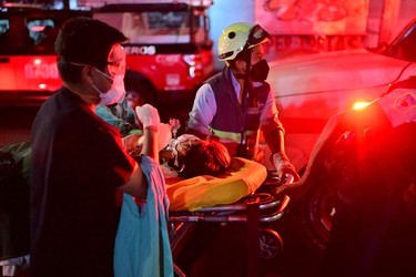 Emergency workers move an injured person on a stretcher at the site of a train accident after an elevated metro line collapsed in Mexico City on May 4, 2021. (Photo by PEDRO PARDO/AFP via Getty Images)