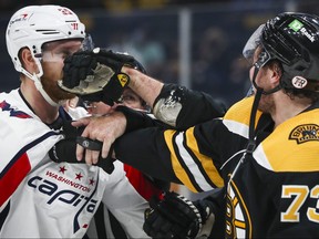 Anthony Mantha, left, of the Washington Capitals is punched by Brad Marchand while being pushed by Charlie McAvoy of the Boston Bruins in the second period in Game 4 of the First Round of the 2021 Stanley Cup Playoffs at TD Garden on May 21, 2021 in Boston.