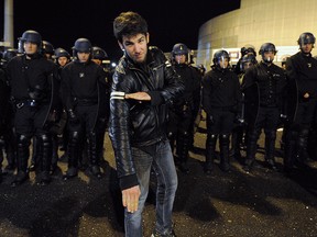 A man performs a "quenelle" salute next to a line of French police officers on January 9, 2014 at the Zenith in Saint-Herblain, western France.