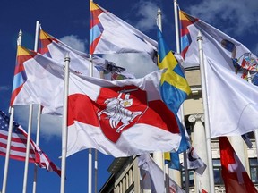 A historical white-red-white flag of Belarus flies next to national flags of nations participating in the IIHF World Ice Hockey Championships in Riga, Latvia, Monday, May 24, 2021.