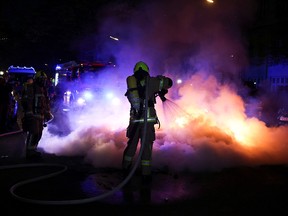 Firefighters work to extinguish a fire during a left-wing May Day demonstration, as the spread of the coronavirus continues in Berlin, May 1, 2021.