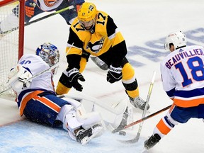 Penguins forward Bryan Rust, centre, attempts a shot against Islanders goaltender Semyon Varlamov as Anthony Beauvillier defends during the second period in Game 2 of the First Round of the 2021 Stanley Cup Playoffs at PPG PAINTS Arena in Pittsburgh, Tuesday, May 18, 2021.