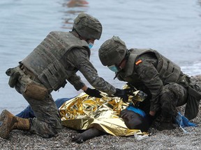Spanish legionnaires attend to a Moroccan citizen on El Tarajal beach, near the fence between the Spanish-Moroccan border, after thousands of migrants swam across this border on Monday, in Ceuta, Spain, May 18, 2021.