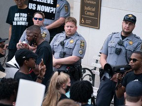 Police officers watch as protestors call for justice for Jamal Sutherland on May 17, 2021 outside of the Charleston County Judicial Center in Charleston, South Carolina.
