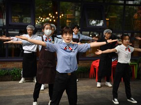 Restaurant staff perform a dance during a team building exercise outside their restaurant in Beijing on May 14, 2021.