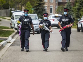 Officers with York Regional Police bring flowers to the  memorial at the scene of a Sunday crash that claimed the life of a four-year-old boy on Athabasca Dr., south of Dufferin St. and Kirby Rd., in Vaughan on Monday, May 17, 2021.