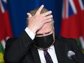 Ontario Premier Doug Ford wipes his head as he holds a press conference regarding the plan for Ontario to open up at Queen's Park during the COVID-19 pandemic in Toronto May 20, 2021.