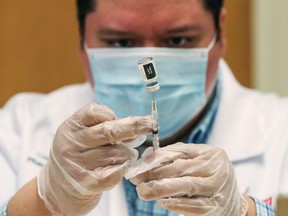 Walgreens healthcare professional Luis S. Solano prepares a dose of the Pfizer-BioNTec vaccine at the Victor Walchirk Apartments in Evanston, Ill., Feb. 22, 2021.  REUTERS