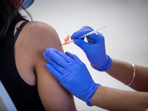 A woman receives her first dose of the Pfizer COVID-19 vaccine at an immunization clinic at the Gurdwara Dukh Nivaran Sahib, in Surrey, B.C., on Friday, May 14, 2021.