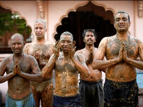 People pray after applying cow dung on their bodies during "cow dung therapy," believing it will boost their immunity to defend against COVID-19 at the Shree Swaminarayan Gurukul Vishwavidya Pratishthanam Gaushala or cow shelter on the outskirts of Ahmedabad, India, May 9, 2021.