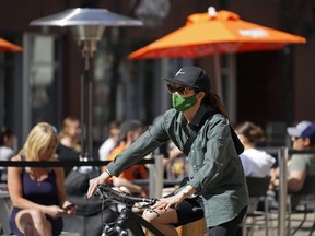 A cyclist pedals past outdoor diners on 104 Street in downtown Edmonton, April 17, 2021, where the street was closed to motor vehicles to allow restaurants to serve patrons outside on the street during the COVID-19 pandemic.