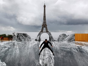 A man poses on a giant artwork by French artist JR installed on the Trocadero square in front of the Eiffel Tower in Paris, France, May 19, 2021.