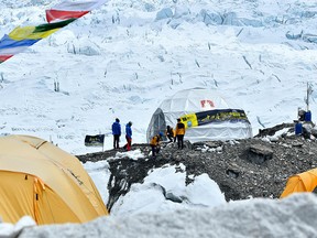 In this picture taken on May 1, 2021 expedition members clear an area to set up tents at Everest base camp in the Mount Everest region of Solukhumbu district.