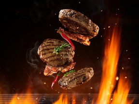 Flying beef hamburgers pieces above burning grill