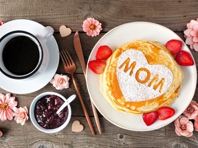 Mothers Day breakfast pancakes with heart shape and MOM letters, overhead view table scene on rustic wood