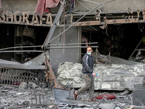 A Palestinian man walks past damaged shops in the aftermath of Israeli air strikes that destroyed a tower building, amid a flare-up of Israeli-Palestinian violence, on the first day of Eid al-Fitr holiday, in Gaza City May 13, 2021.