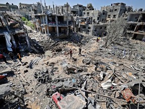 Palestinians assess the damage caused by Israeli air strikes, in Beit Hanun in the northern Gaza Strip, on May 14, 2021.