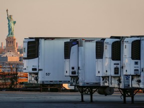Refrigerated tractor trailers used to store bodies of deceased people are seen at a temporary morgue, with the Statue of Liberty seen in the background, during the COVID-19 outbreak, in the Brooklyn borough of New York City, May 13, 2020.