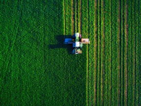 Tractor mowing green field, aerial view.