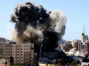 A thick column of smoke rises from the Jala Tower as it is destroyed in an Israeli airstrike in Gaza city controlled by the Palestinian Hamas movement, on May 15, 2021.