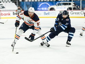Oilers captain Connor McDavid (left) carries the puck against Winnipeg Jets forward Nate Thompson on Monday night. Edmonton lost in triple overtime and was swept from the series.