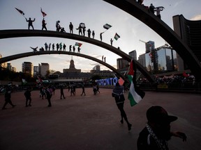 Demonstrators wave flags atop the arches of Toronto City Hall as thousands gather in Toronto, Ontario, Canada to show their support for the people of Palestine on May 15, 2021.
