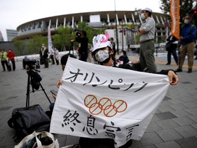 Anti-Olympics protester shows off a banner with the National Stadium for the games in the background outside the Japanese Olympic Committee headquarters during a rally in Tokyo May 18, 2021.