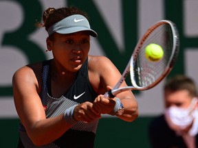 Naomi Osaka returns the ball to Patricia Maria Tig during their first-round match at the French Open in Paris on May 30, 2021.