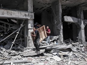 Palestinian men remove salvageable items from the bombarded Al-Jawhara Tower in Gaza City on May 17, 2021, five days after it was targeted by Israeli airstrikes.