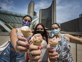 Nadia Karimy (who was previously vaccinated) enjoys some free ice-cream after her daughters Victoria, 17 (left) and Elizabeth got their vaccination at a pop-up clinic at Nathan Philips Square in Toronto on Sunday May 23, 2021.