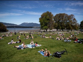 In this May 9, 2020 file photo, people sit and lie in the sun at Kitsilano Beach Park as temperatures reached highs into 20s in Vancouver according to Environment Canada.