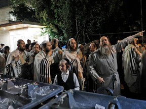 Ultra Orthodox Jewish men and children gather at the scene where a grandstand seating at a synagogue collapesed in the Israeli settlement of Givat Zeev in the occupied West Bank outside Jerusalem, on May 16, 2021.