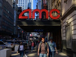 People walk past an AMC and IMAX movie theatre in the theatre district near Broadway on May 6 2021 in New York City.