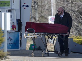 A worker with the medical examiner's office removes the body of Gabriel Wortman from a gas bar in Enfield, N.S. on Sunday, April 19, 2020.