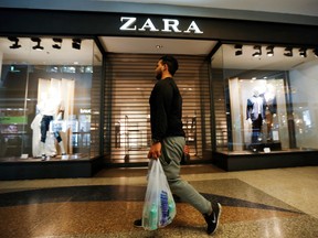 A man walks past a Zara retail store, with its shutters drawn, at a mall in Caracas September 30, 2014.