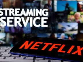 A smartphone with the Netflix logo is seen on a keyboard in front of displayed "Streaming service" words in this illustration taken March 24, 2020.