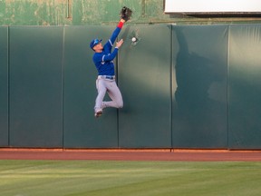 Blue Jays right fielder Cavan Biggio (8) crashes into the wall trying to catch a deep fly ball hit by Oakland Athletics' Jed Lowrie during the second inning at the Coliseum on Monday night.