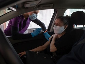 Nurse Gurinder Rai, left, administers the Moderna COVID-19 vaccine to Maria Yule at a Fraser Health drive-thru vaccination site, in Coquitlam, B.C., on Wednesday, May 5, 2021.