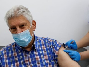 An elderly person receives a dose of the Oxford/AstraZeneca COVID-19 vaccine at Cullimore Chemist, in Edgware, London, England, Jan. 14, 2021.
