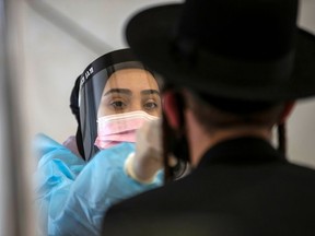 A healthcare worker takes a swab sample from an Ultra-Orthodox Jewish man for the coronavirus disease (COVID-19) test, after returning from overseas, at Ben Gurion International Airport in Lod, near Tel Aviv, Israel April 13, 2021.