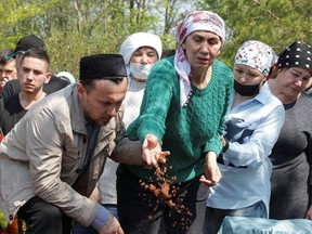A mourner throws soil into the grave of Elvira Ignatieva, an English language teacher killed in the massacre at School Number 175, during a funeral at a cemetery in Kazan, Russia May 12, 2021.