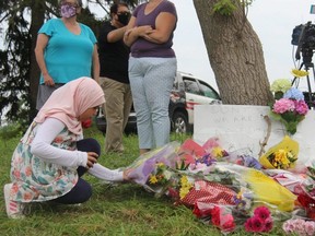 Nine-year-old Shahed Mahmoud places a flower arrangement at the corner of Hyde Park and South Carriage roads, where an impromptu memorial was created for the members of a Muslim family killed Sunday night. (JONATHAN JUHA/The London Free Press)