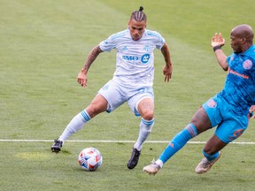 Toronto FC defender Auro Jr. dribbles the ball while Columbus Crew SC midfielder Darlington Nagbe (6) defends.